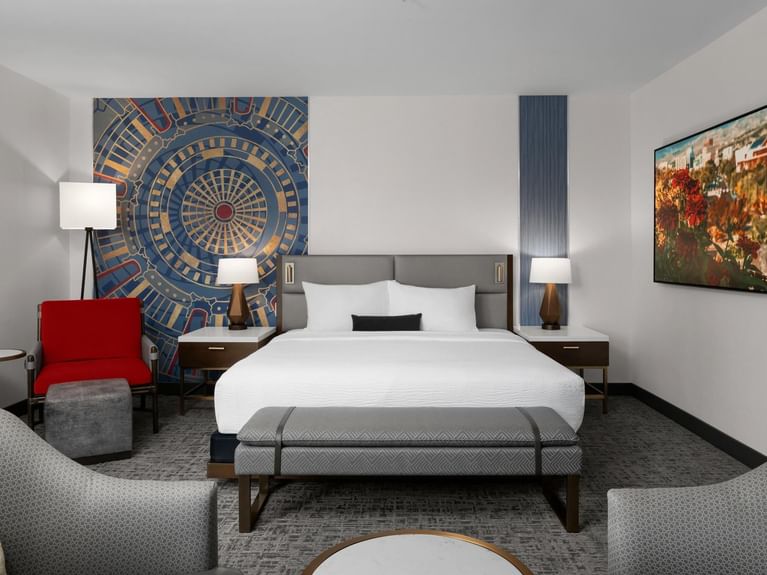 Clean and modern Longitude Suite with a bed, art, and seating, featuring a gold and blue mandala art piece at Hotel 43 Boise