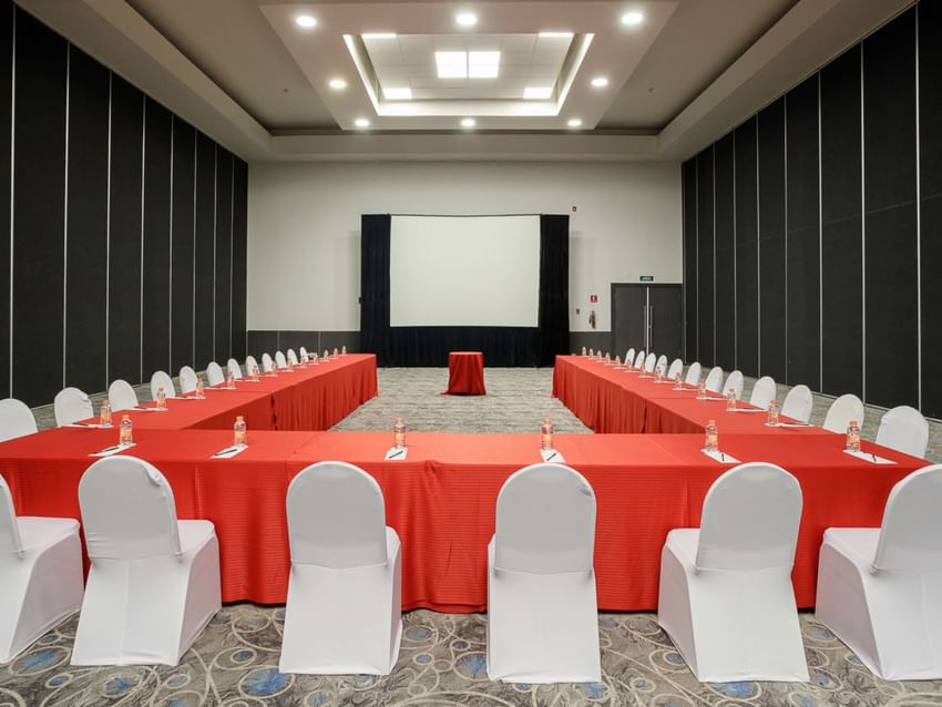 Large conference room with red-covered tables and white chairs at Real Inn Tijuana