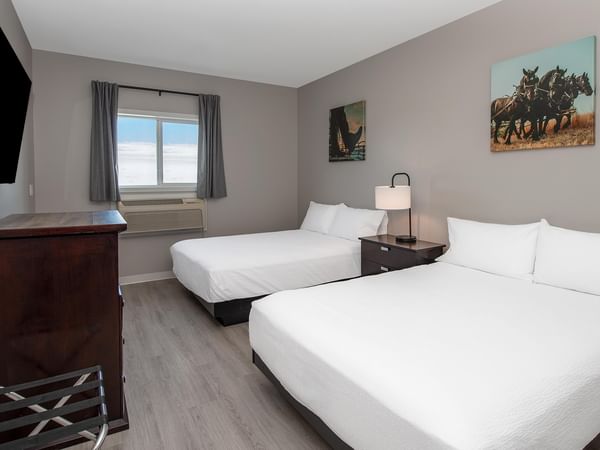 Two beds, dresser, TV, and artwork in a room at Coast Innisfail Hotel.