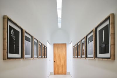 Modern, white hallway with a skylight, featuring framed art on both walls at Singular Signature Residences