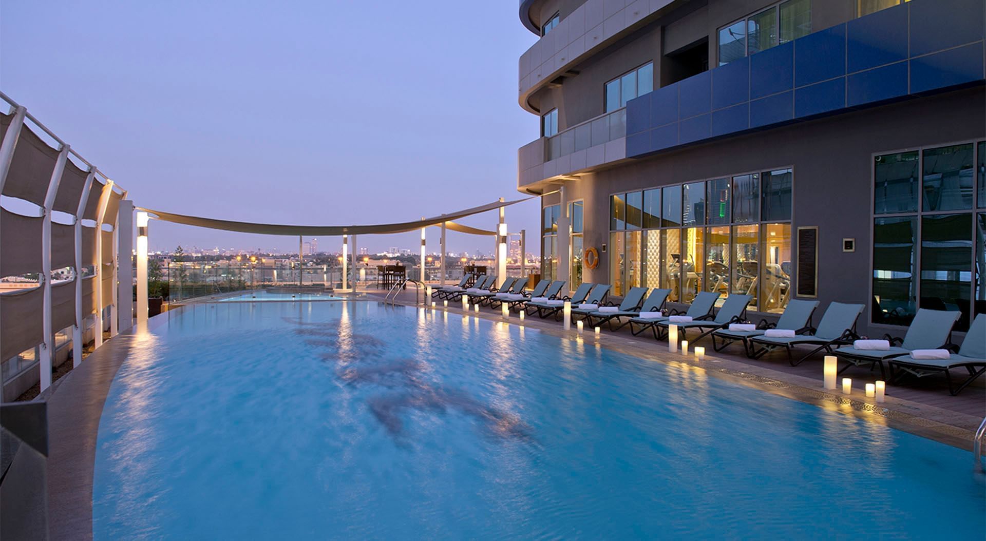 Rooftop pool area with lounge chairs and city skyline view at DAMAC Maison Mall Street