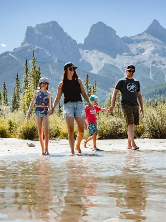 Family holding hands and walking by the river with a mountain backdrop near Spring Creek Vacations