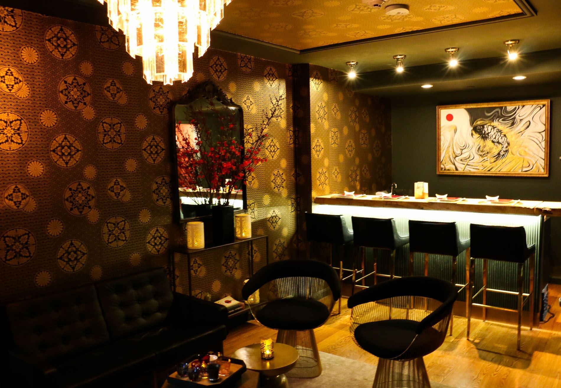 A dimly lit lounge with a bar, sofa, and chairs.