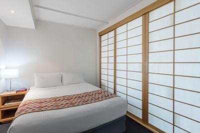 King bed & night lamp in a room at Nesuto Hotels