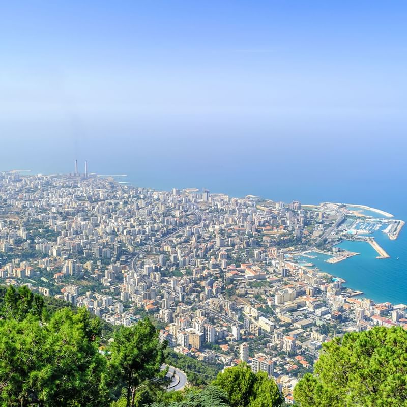 Panoramic view of Beirut's skyline with coastal waters and green hills, showcasing location near Warwick Hotels and Resorts