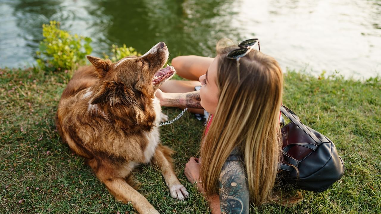 girl with her dog sitting on grass