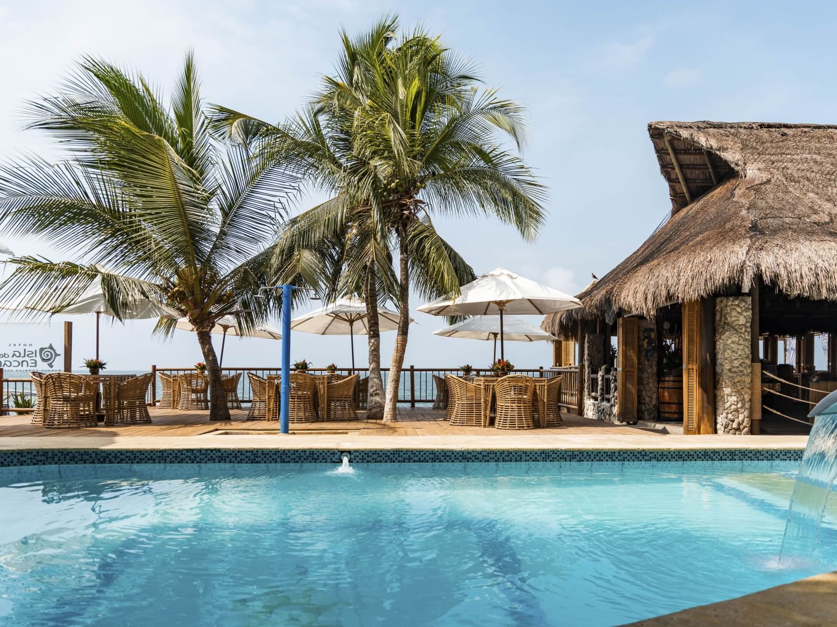 Pool with sitting area with umbrella by sea at Hotel Isla Del Encanto
