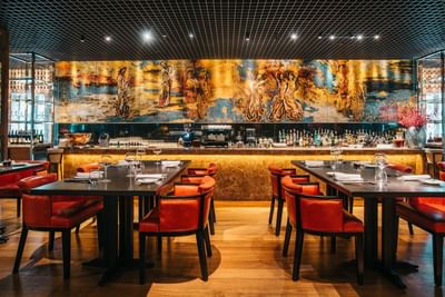 Dining area with vibrant artwork and wooden flooring in Square One Restaurant at Park Hyatt Saigon