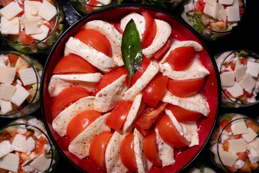 Gros plan sur un plat de salade caprese entouré de coupelles de salade agrémentées de cubes de fromage, au Warwick Paris Champs-Élysées
