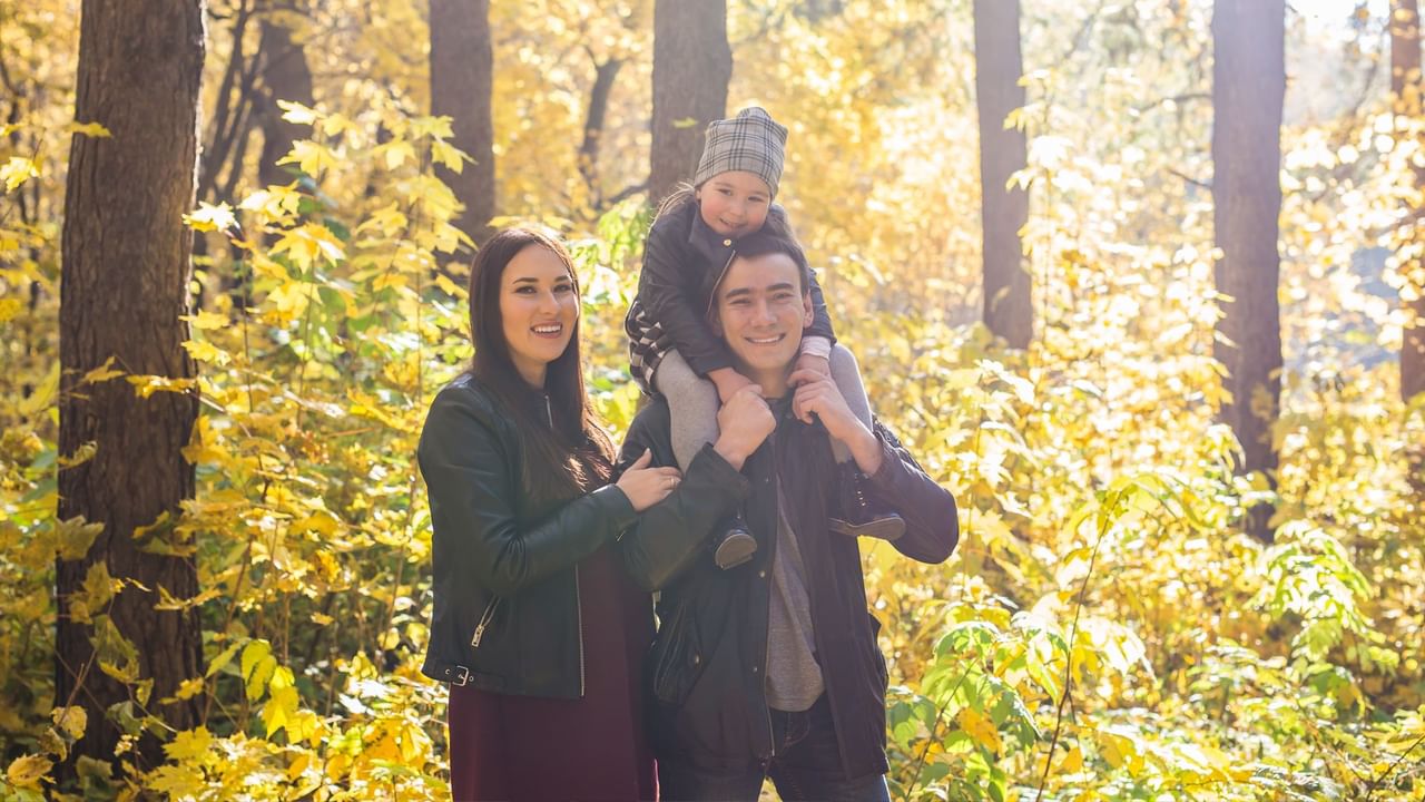 A happy family enjoys a walk through a sunlit autumn forest.