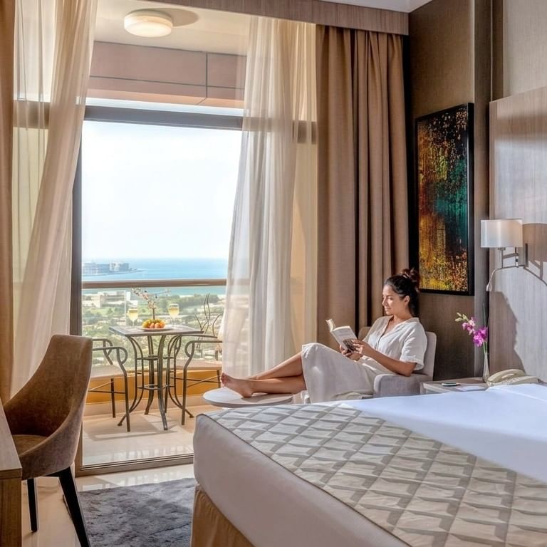 Long stay guest in modern hotel room with ocean view balcony and comfortable seating area in Dubai
