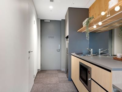 Modern kitchen with gray counters, wooden cabinets, microwave, and sink at La Trobe University.