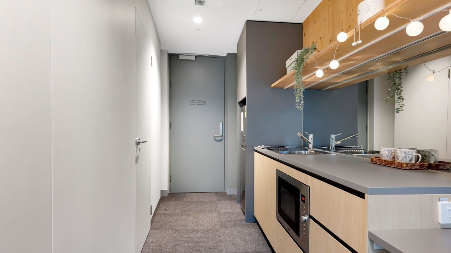 Modern kitchen with gray counters, wooden cabinets, microwave, and sink at La Trobe University.