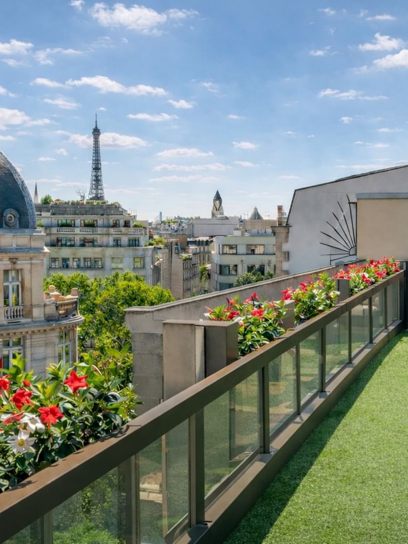 Vue sur les toits de Paris et sur un balcon agrémenté de gazon et de plantes au Warwick Champs-Élysées Paris.