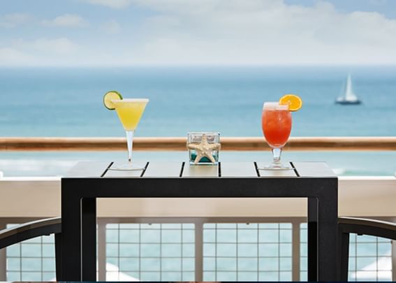 Two cocktails served on a balcony dining table overlooking the ocean view in Surfpoint 360 at Gorges Grant Hotel