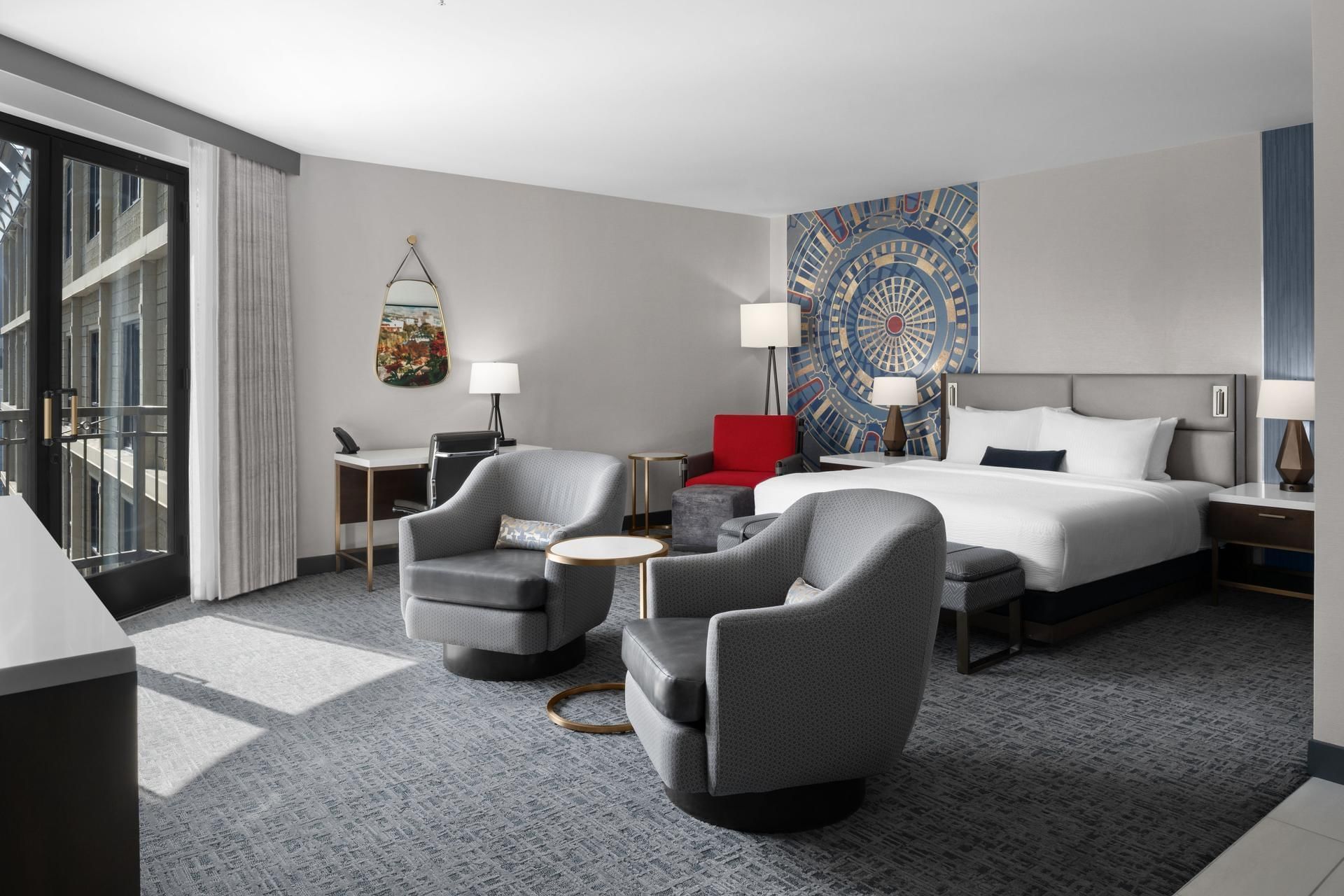 Latitude Suite with a patterned blue mural above the king bed, with two gray chairs at Hotel 43 Boise