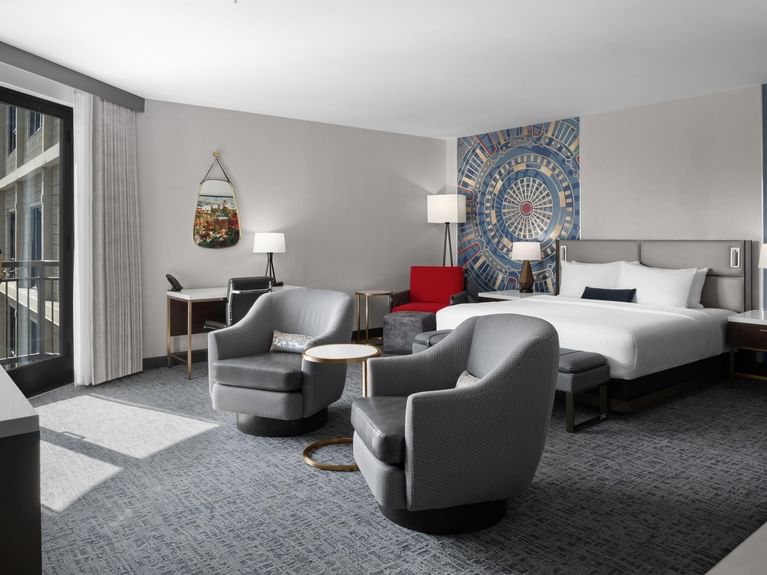 Latitude Suite with a cozy king-sized bed, grey armchairs, and a balcony view at Hotel 43 Boise