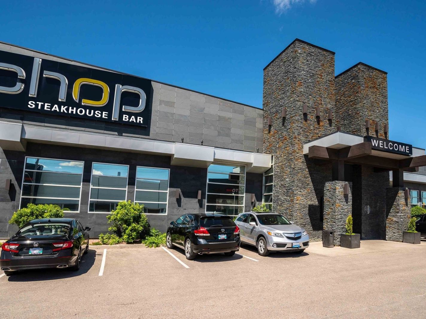 Exterior view of Chop Steakhouse & Bar at Sandman Signature Winnipeg Airport Hotel with vehicles parked