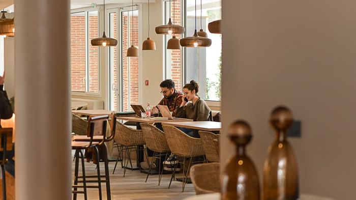 Deux personnes travaillant ensemble à une table dans le salon de l'Hôtel Rivella.