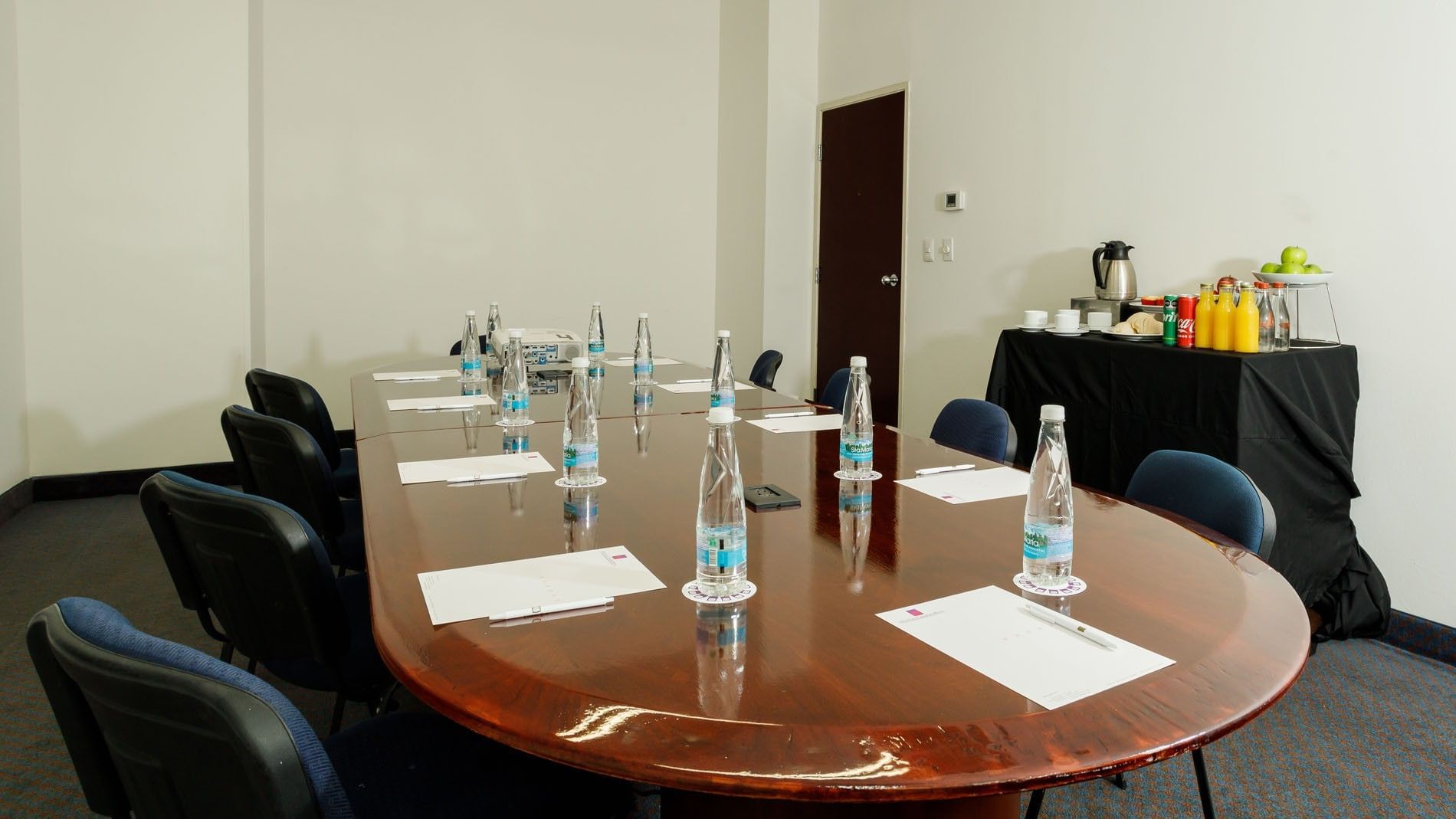 Professional boardroom with a wooden table, water bottles, and catering station at Camino Real Pachuca