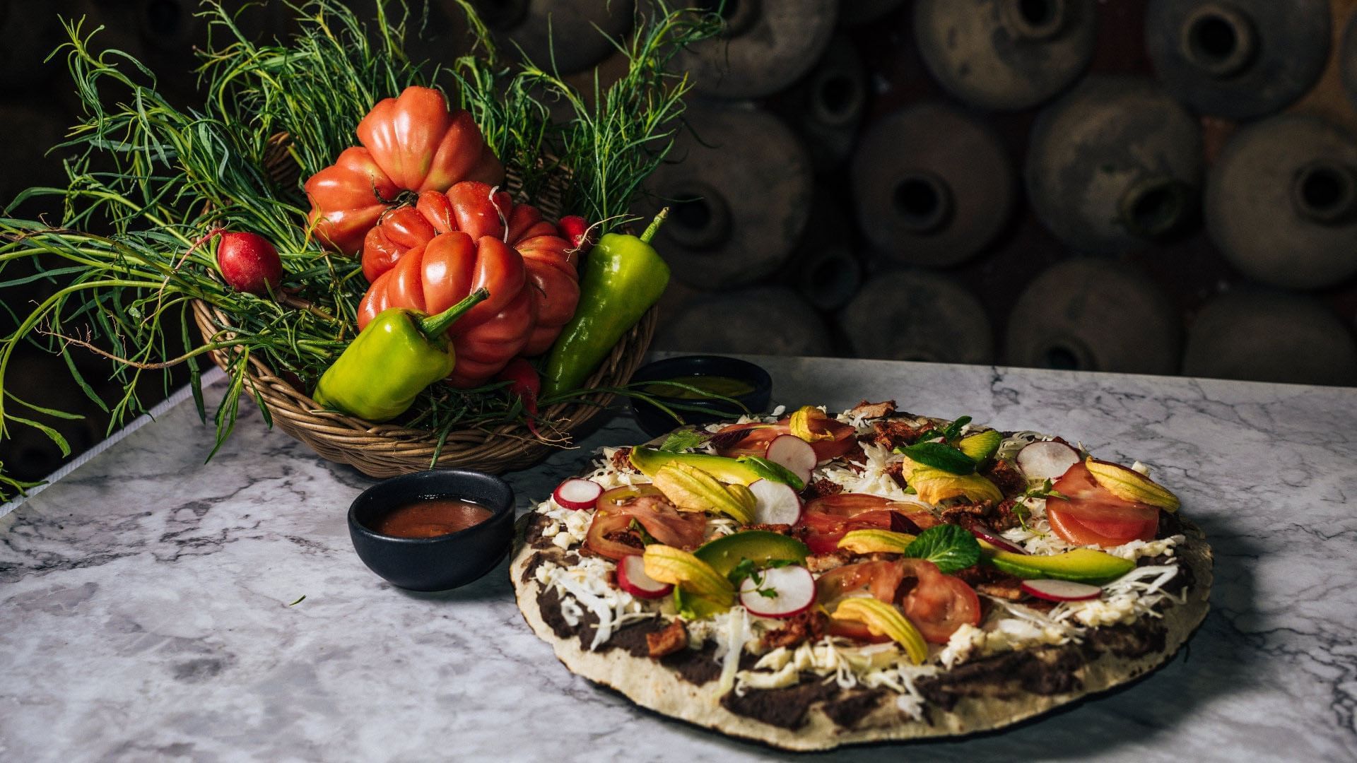 Artisanal flatbread pizza topped with fresh vegetables and served on a marble table at Quinta Real Oaxaca