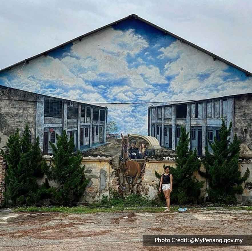 A woman was taking a picture with a huge mural at Bukit Tambun - Lexis Suites Penang