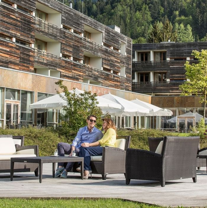 A couple sitting on a couch outside at Falkensteiner Hotels