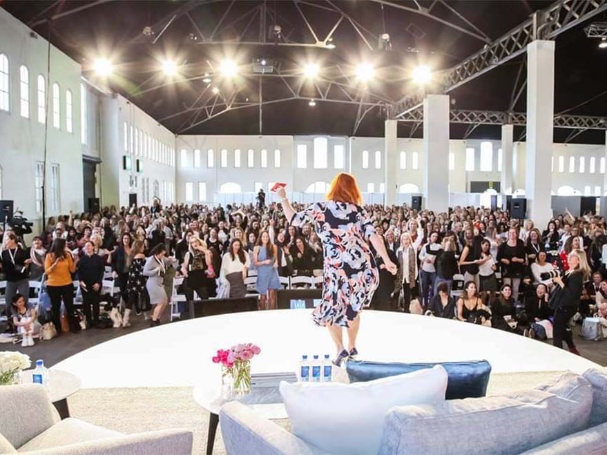 Woman presenting to an audience in a large, well-lit conference hall at Sofitel Brisbane Central