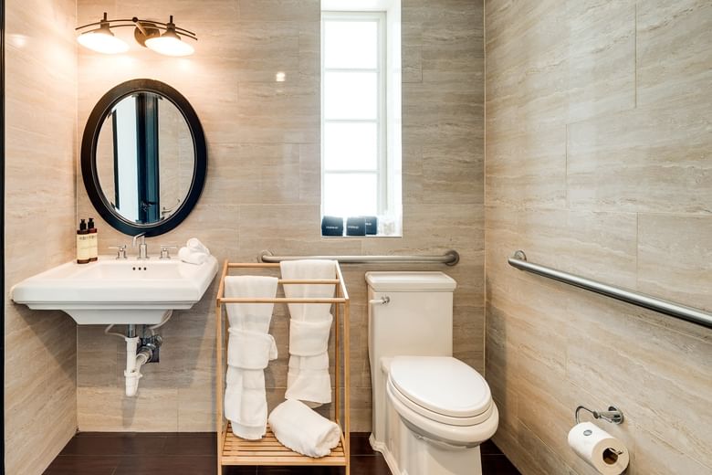 A clean bathroom with a toilet, sink, towels, and grab bar
