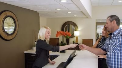 Receptionist hands a key card to guests at Moab Valley Inn’s modern reception desk featuring stylish decor