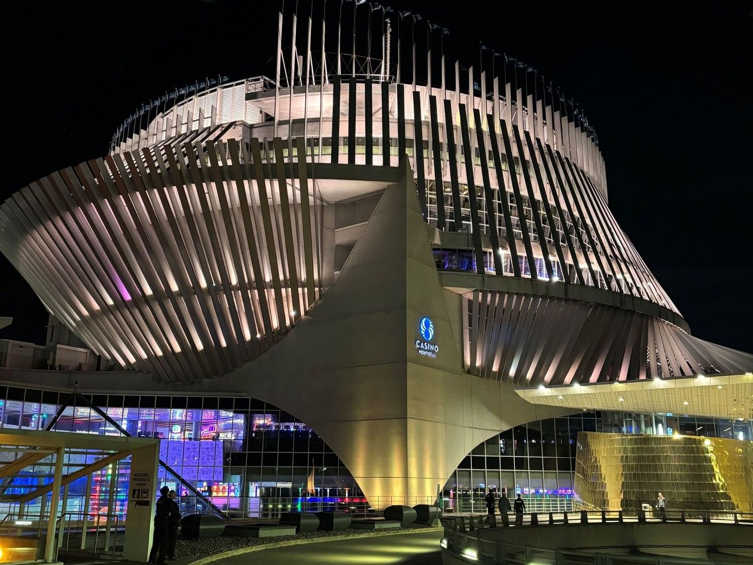 Vue nocturne du Casino de Montréal avec illumination et visiteurs à l'entrée.
