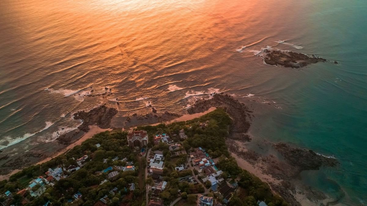 Vista aérea de península costera con vegetación y edificaciones al atardecer en Cala Luna Boutique Hotel
