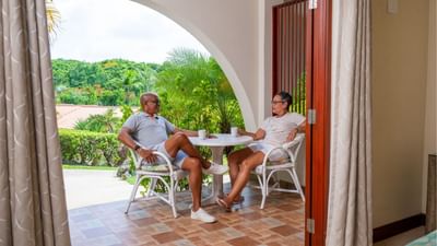 Couple drinking coffee on a private patio view from a bedroom in Garden View Room at Suatgar Cane Club Hotel & Spa