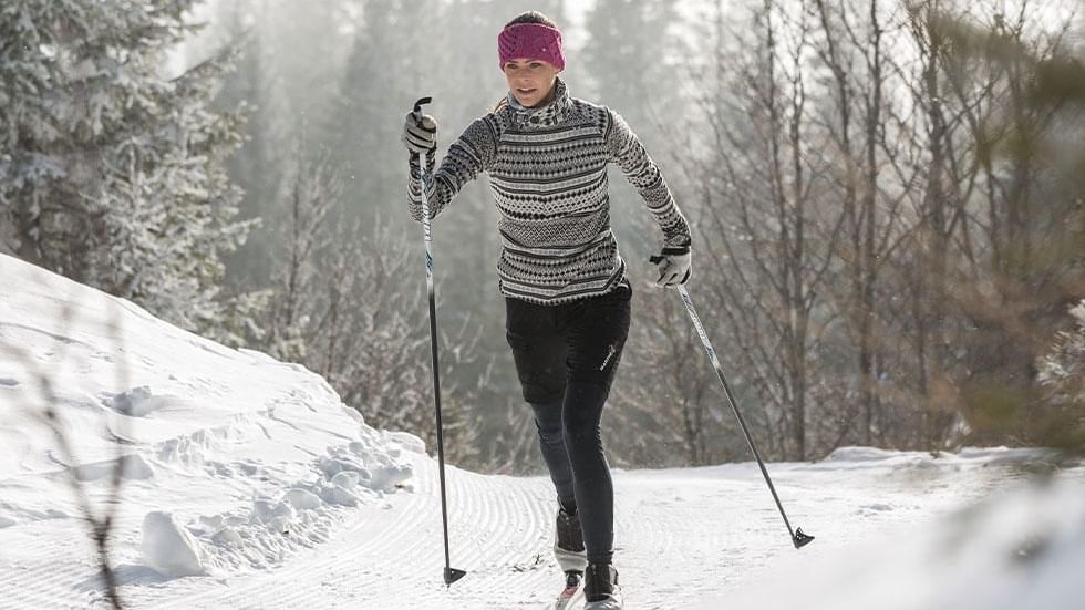 Person cross-country skiing in a snowy forest landscape near Falkensteiner Hotel Kronplatz