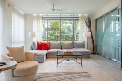Bright living room with large windows overlooking a lush garden in N103 Room at The Residences at Seafire