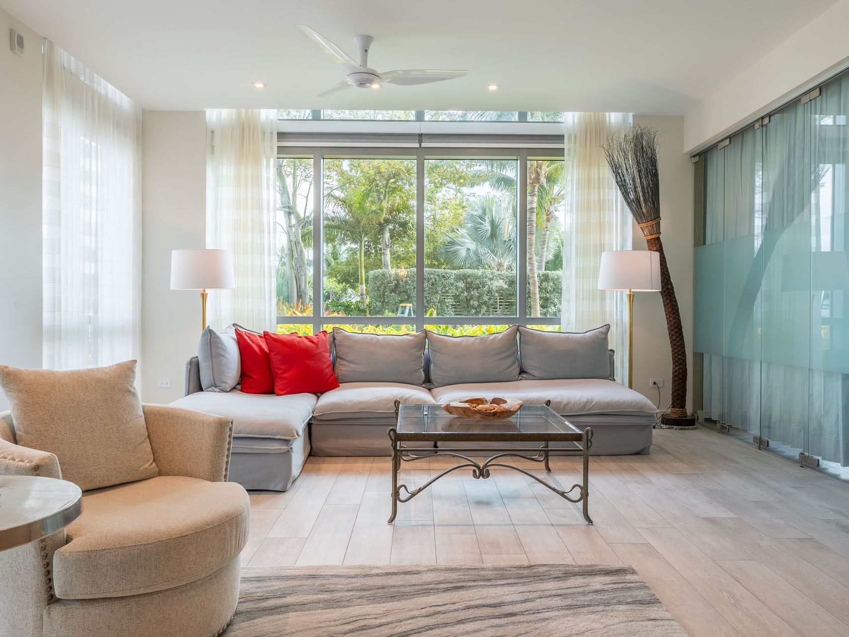 Bright living room with large windows overlooking a lush garden in N103 Room at The Residences at Seafire.