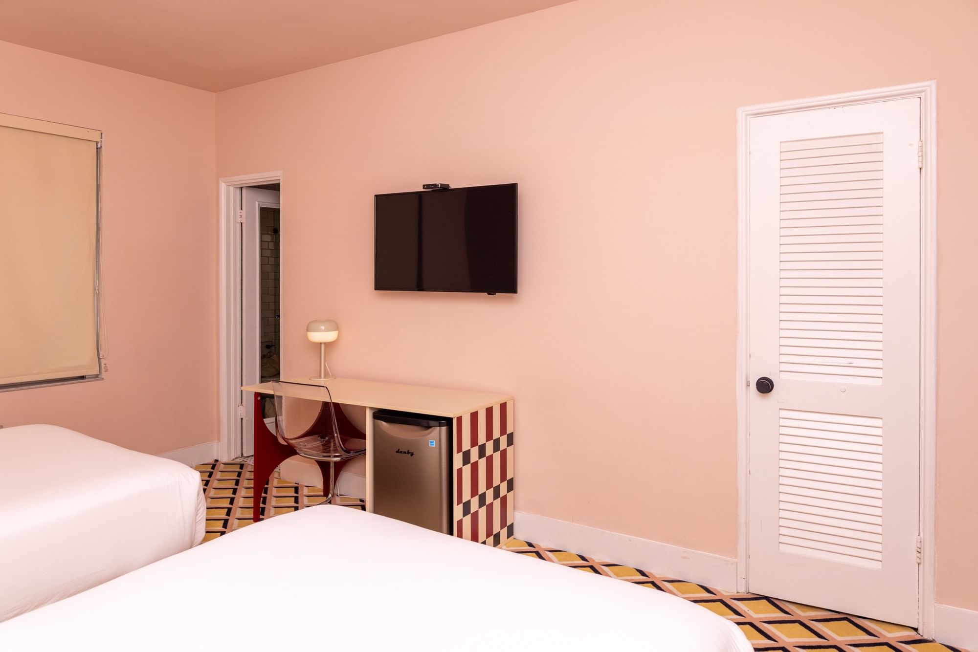 A standard hotel room with two beds, a desk, and a TV