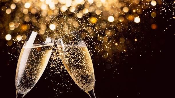 Celebratory toast with two glasses of bubbly champagne under a shower of golden glitter at Seaton House