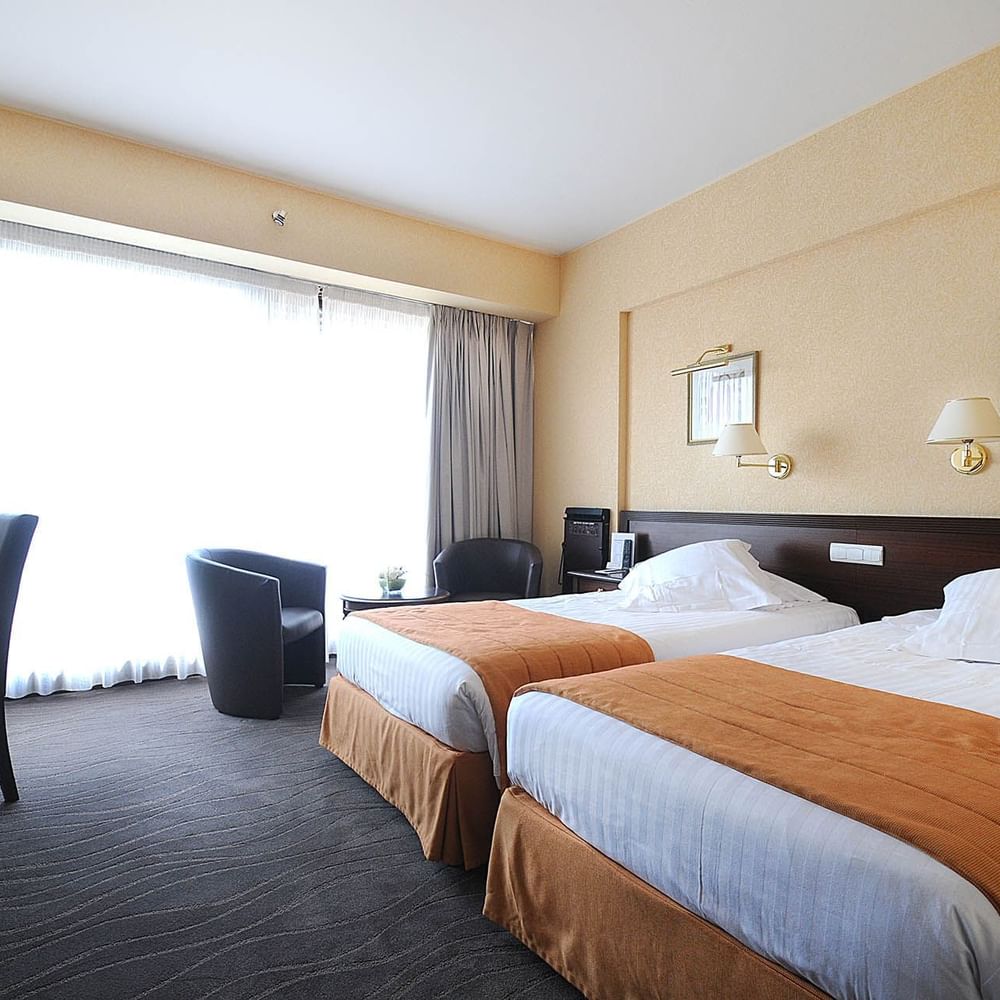 Deluxe Room featuring twin beds with orange runners and a private work station at Splendid Hotel & Spa Nice