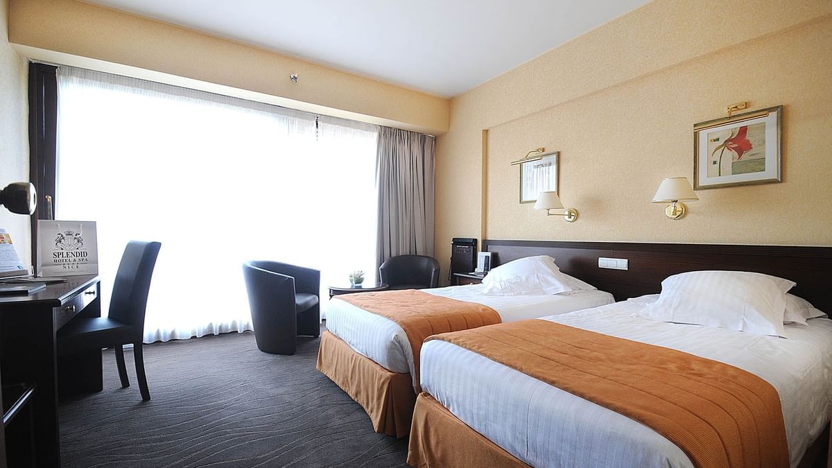 Deluxe Room featuring twin beds with orange runners and a private work station at Splendid Hotel & Spa Nice
