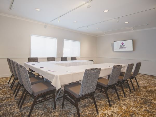 Meeting room with long table, chairs, and TV.