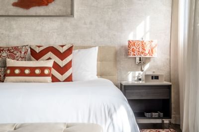 cozy bed with white sheets and red pillow