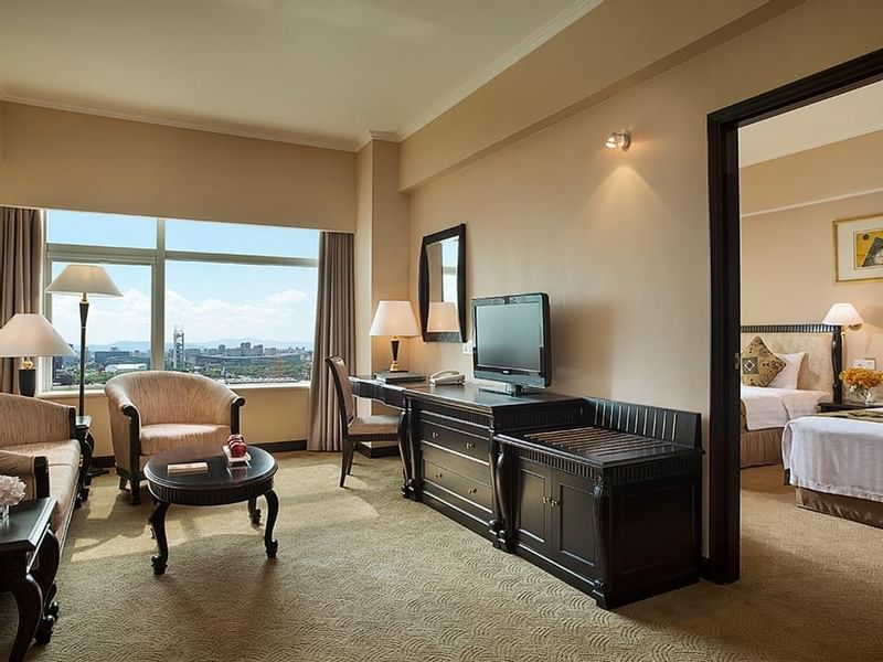 Living area with cozy chairs and a TV in Business Suite at Celebrity International Grand Hotel