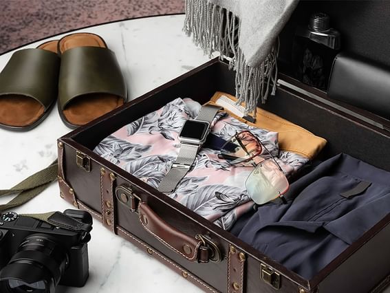 A suit case open with camera, slides, clothes at Park Hotel Group