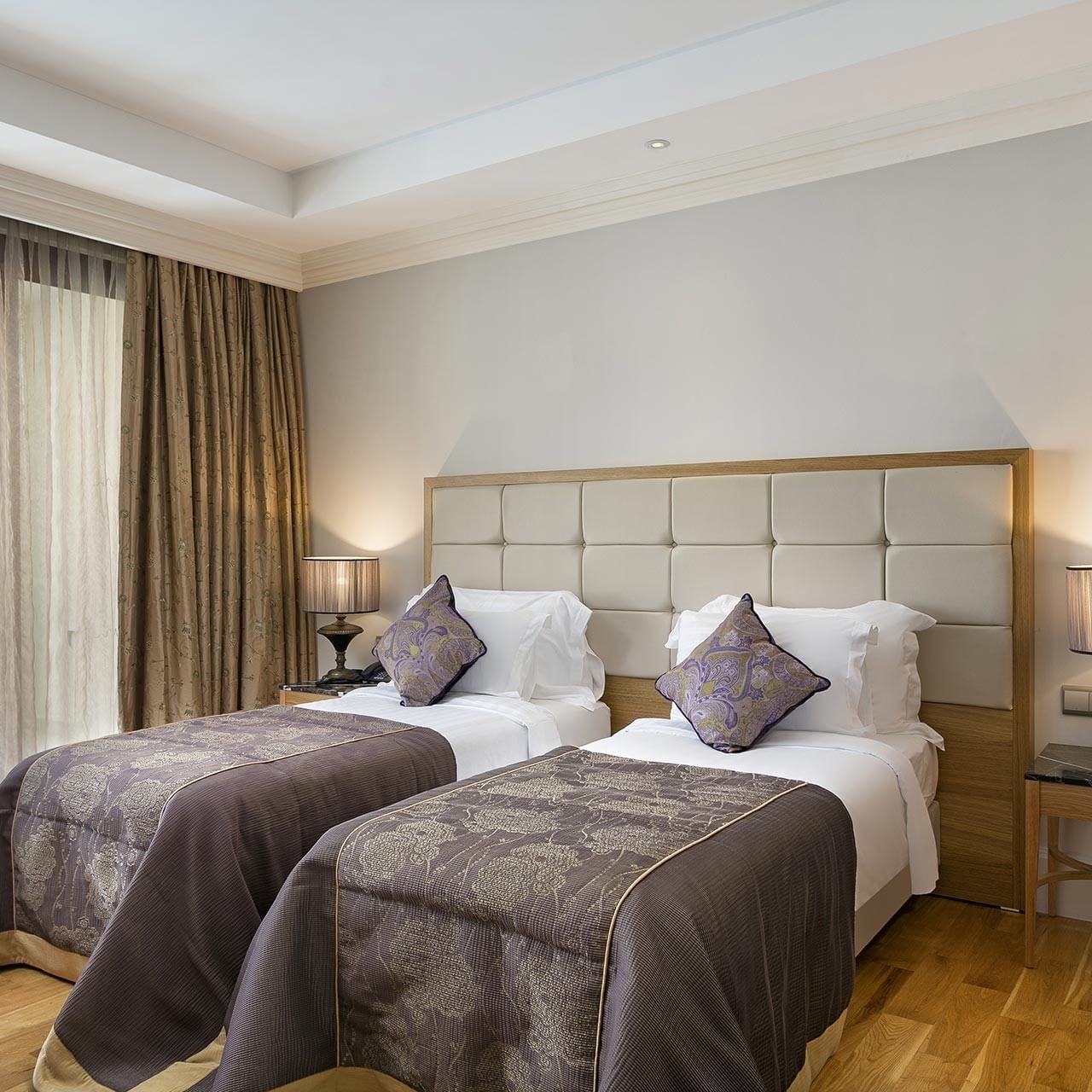 Две кровати с подушками и лампами по обе стороны в гранд двухуровневом люксе отеля Titanic Mardan Palace