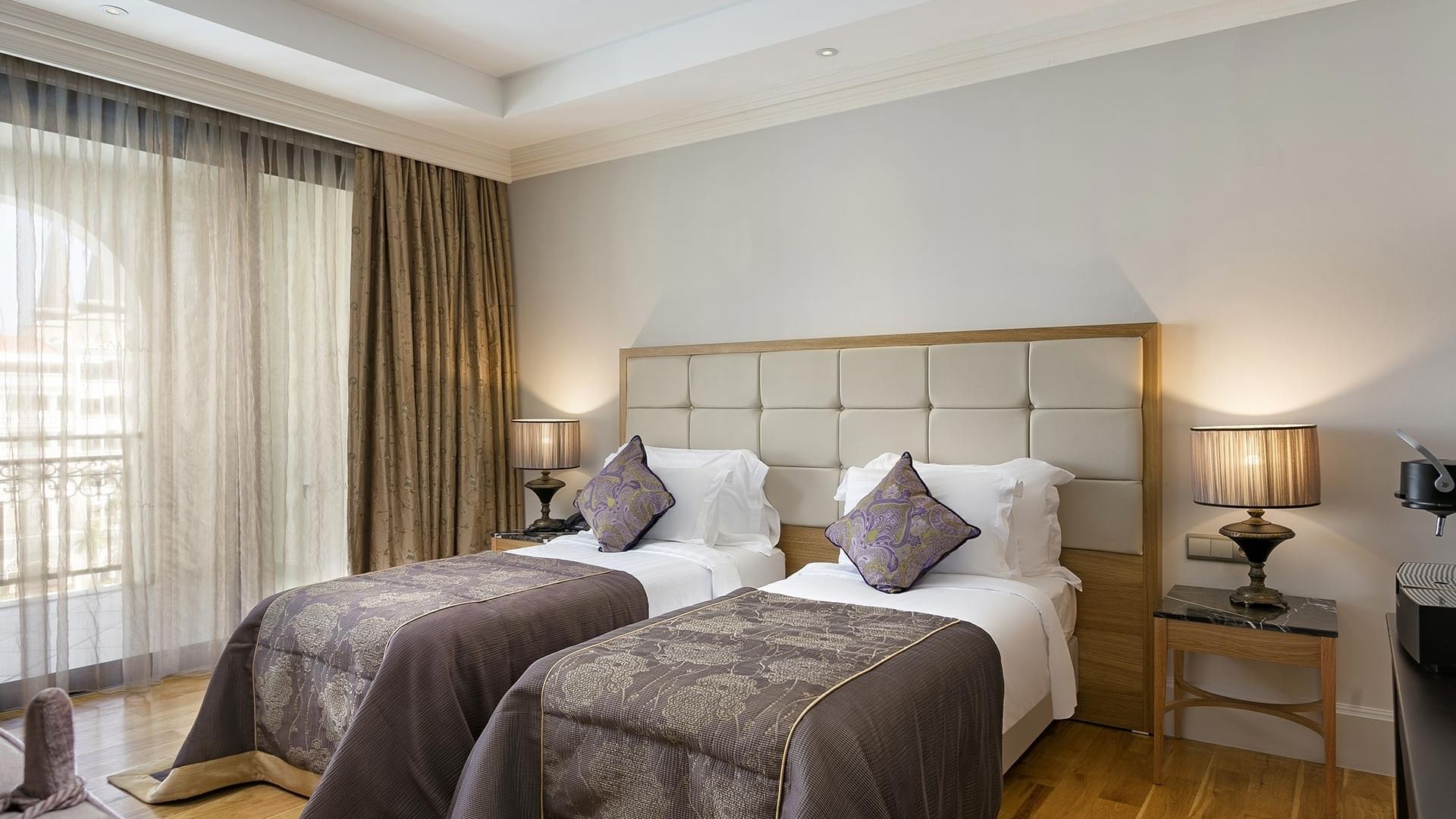 Две кровати с подушками и лампами по обе стороны в гранд двухуровневом люксе отеля Titanic Mardan Palace