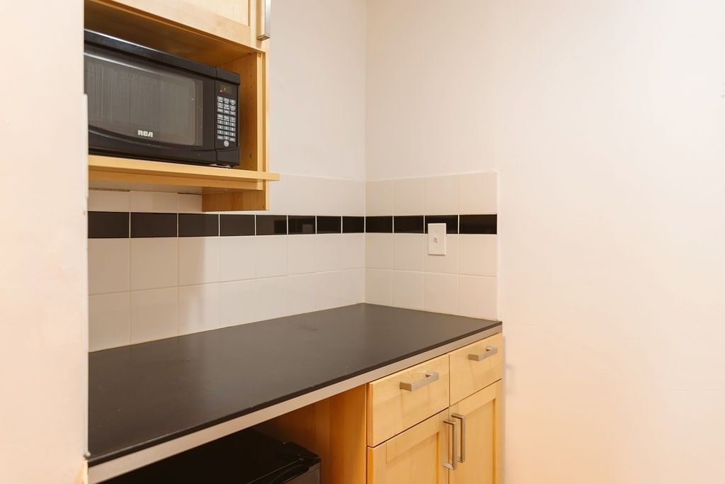 A kitchenette with a microwave, cabinets, and countertop.