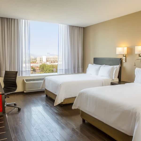 Interior of a room with twin beds and desk at Fiesta Inn