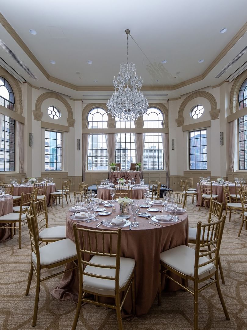 Elegantly set banquet tables and chairs under chandeliers in Tip Top Tap South at Warwick Allerton Chicago