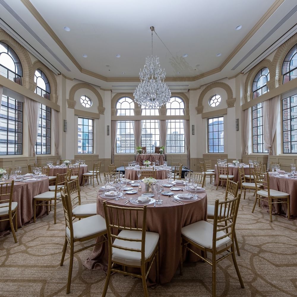 Elegantly set banquet tables and chairs under chandeliers in Tip Top Tap South at Warwick Allerton Chicago